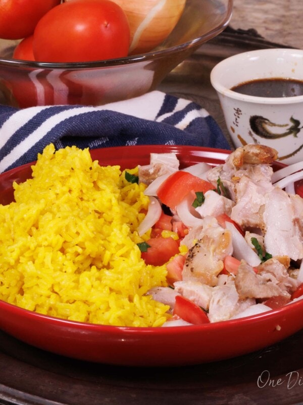 chicken and rice in a red bowl next to a bowl of soy sauce