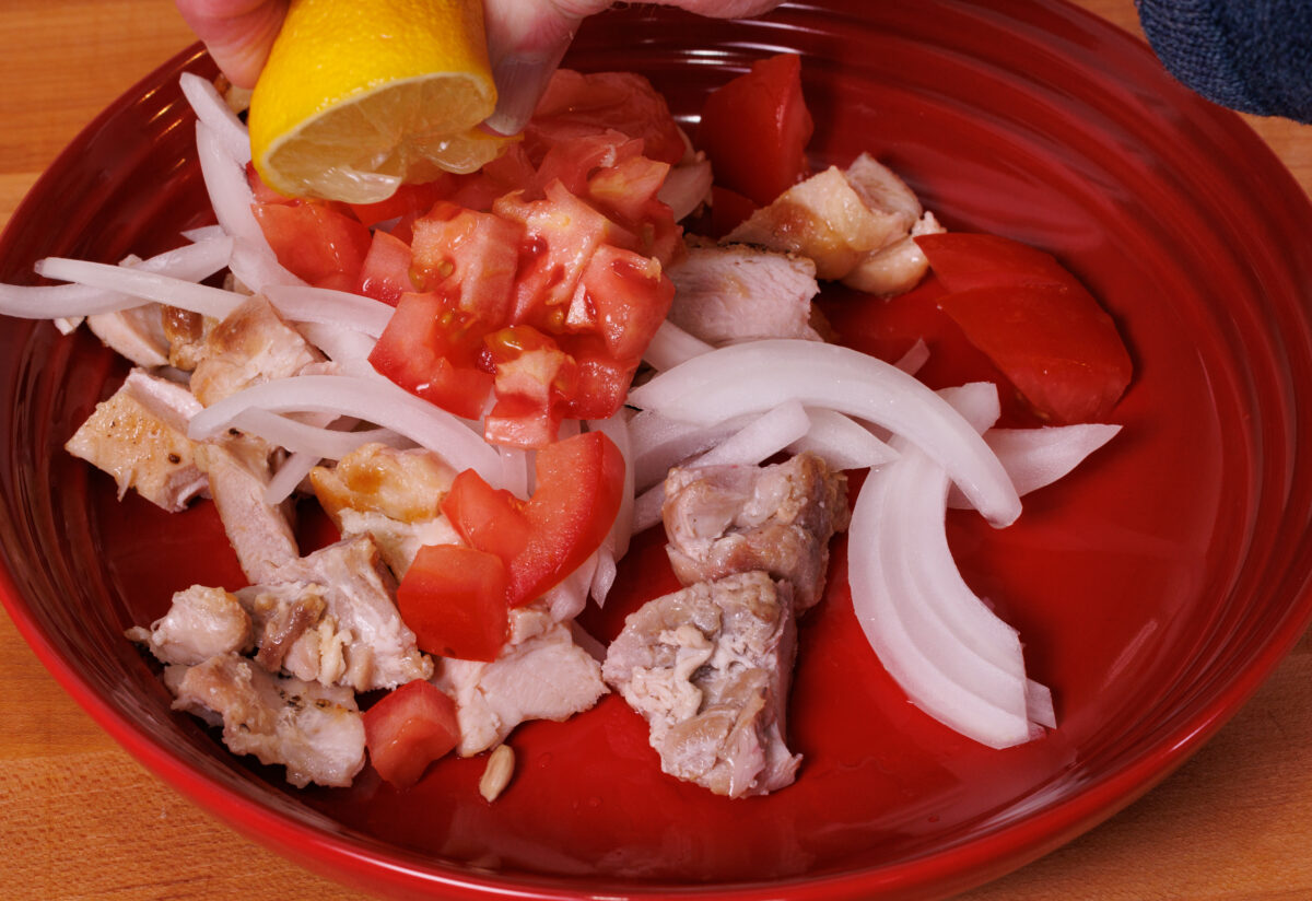 chicken, tomatoes, and onions in a large red bowl.