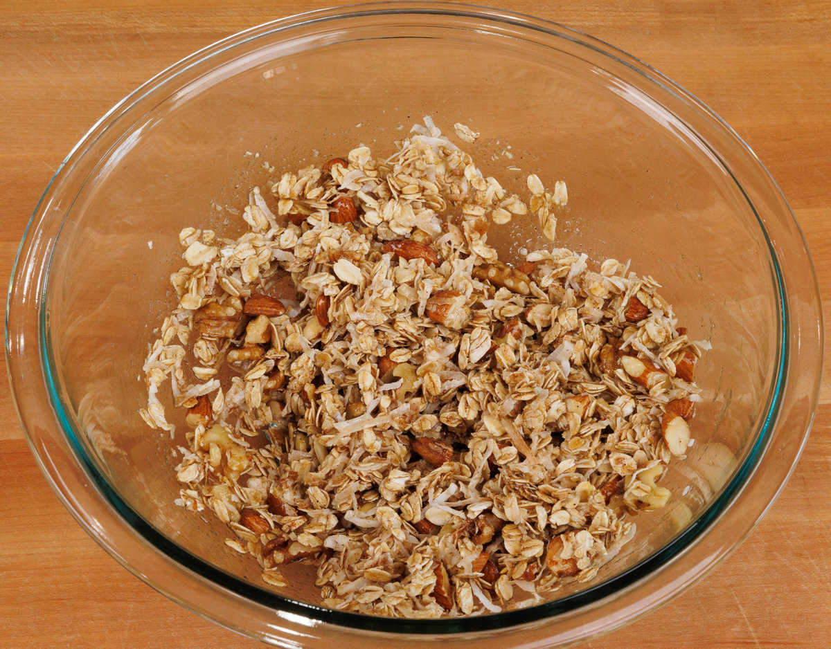 melted butter and maple syrup poured over a bowl of oats and nuts.