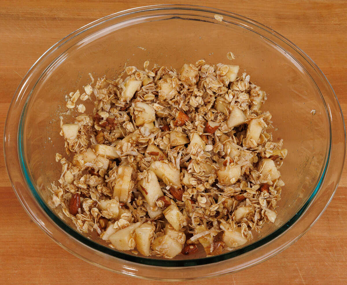 fresh chopped apples in a bowl of unbaked granola.