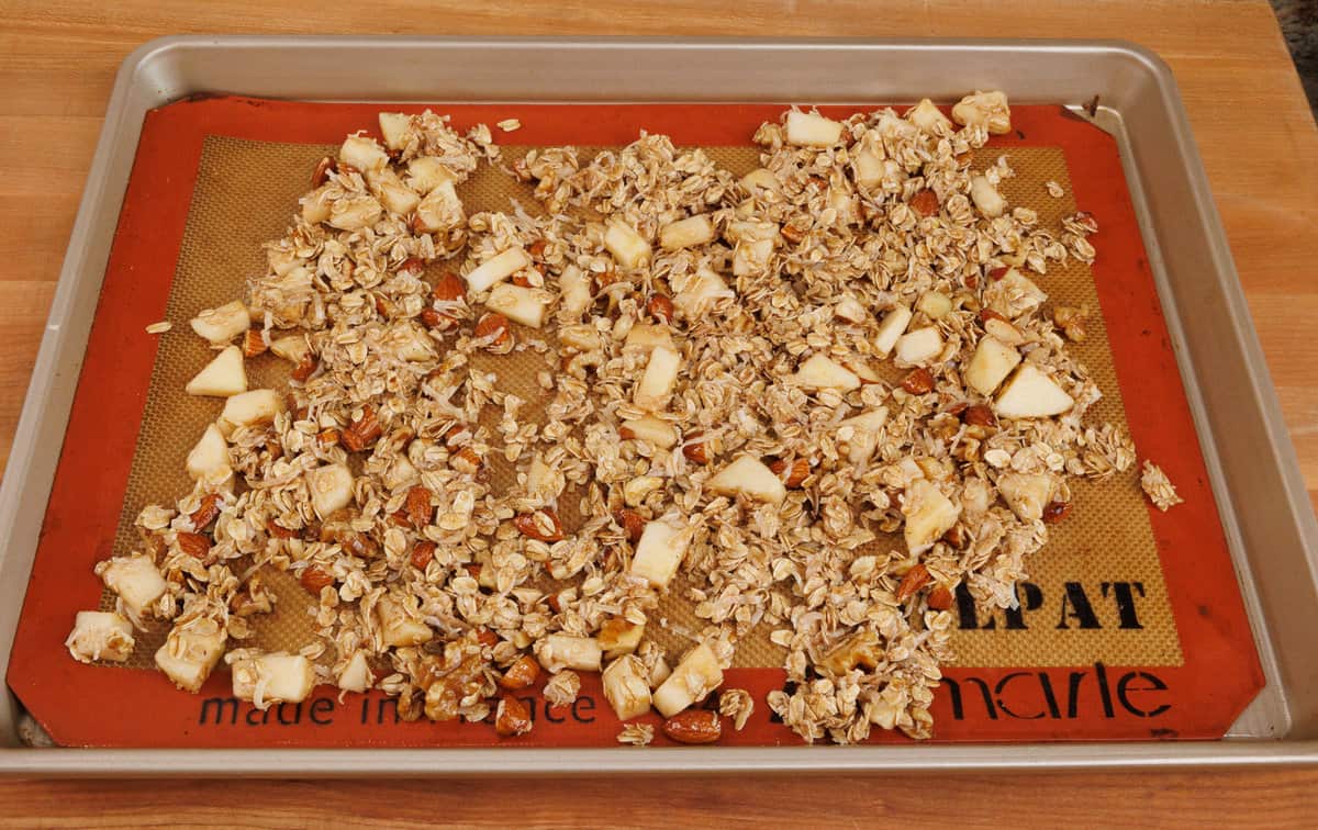 unbaked apple granola on a rimmed baking sheet.