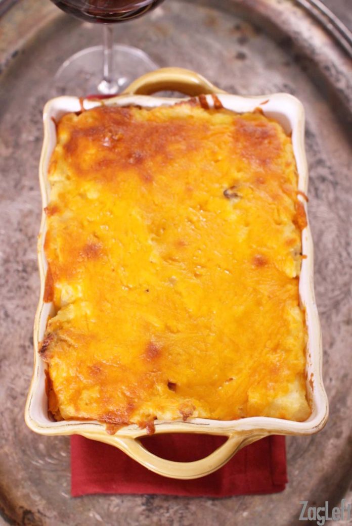 Twice Baked Potato Casserole in a baking dish on a metal tray with a glass of red wine