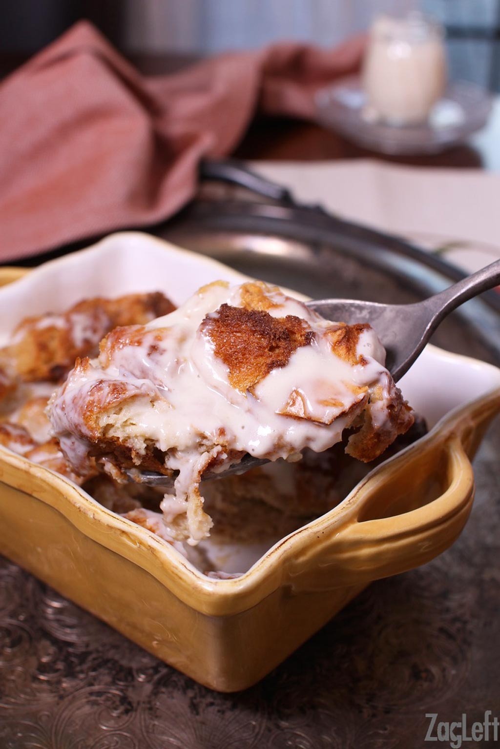 A spoonful of bread pudding with whiskey sauce from baking dish.