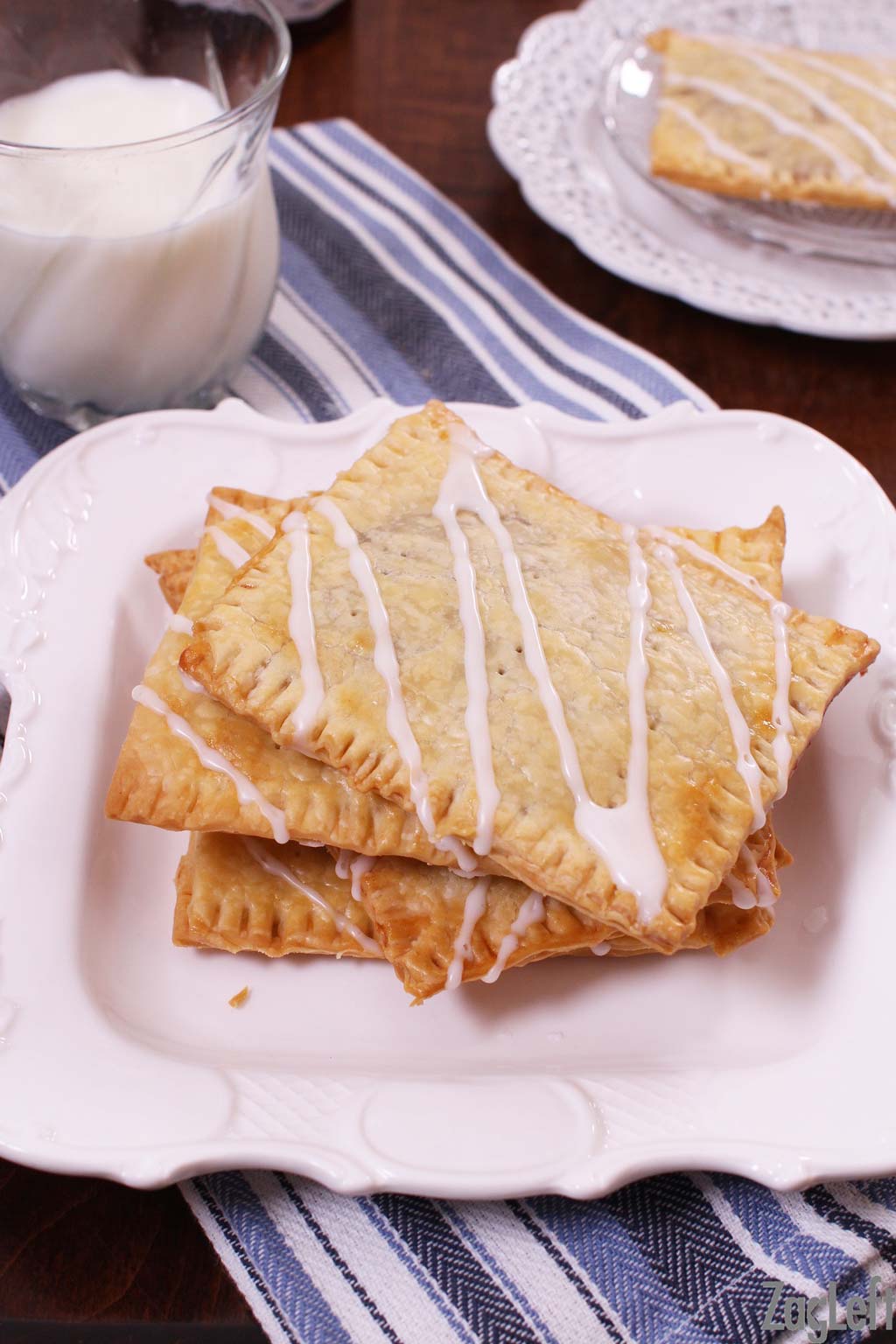 A stack of four homemade toaster pastries on a plate next to a glass of milk.