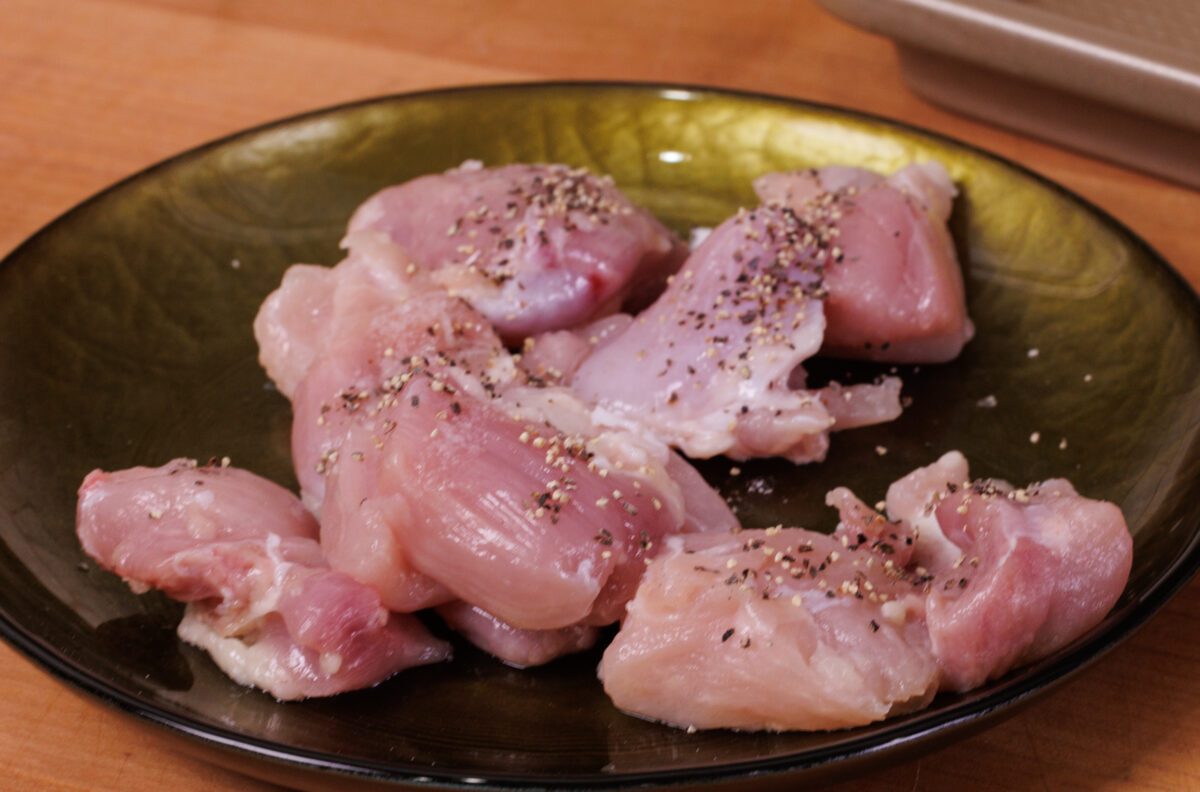 one chicken thigh cut into 1-inch pieces on a green plate