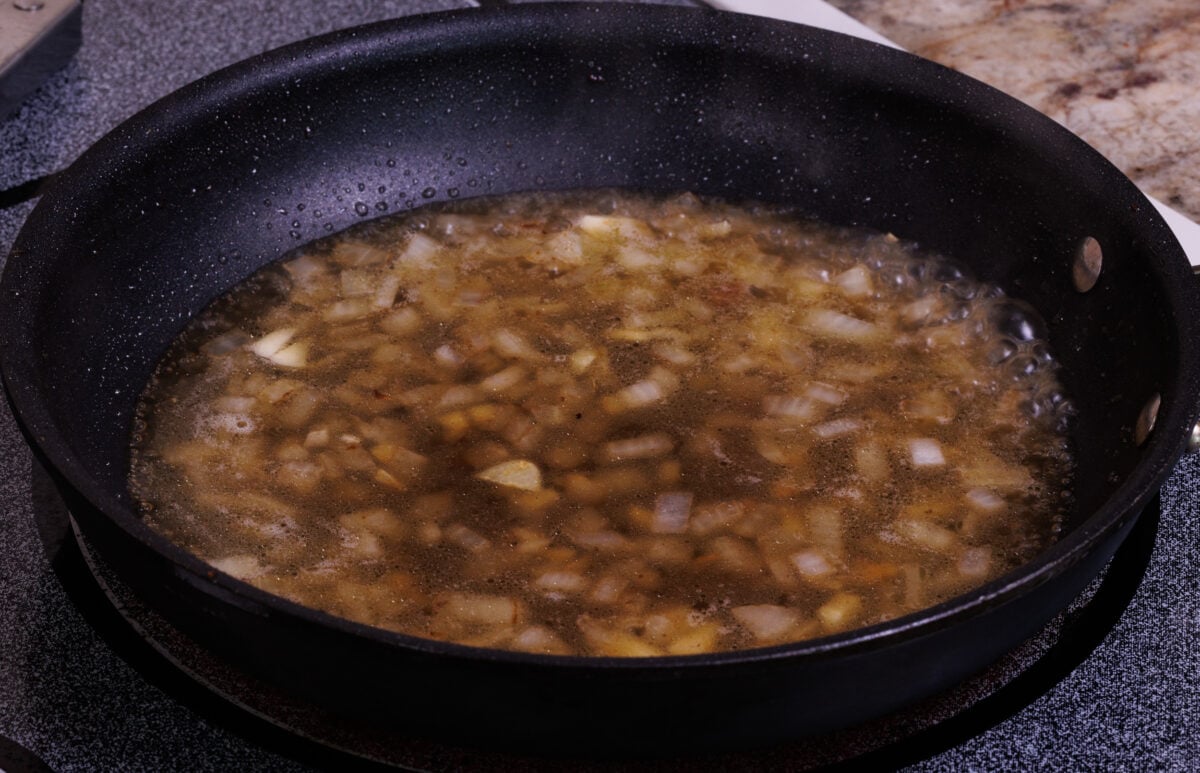 broth simmering in a skillet with onions and garlic