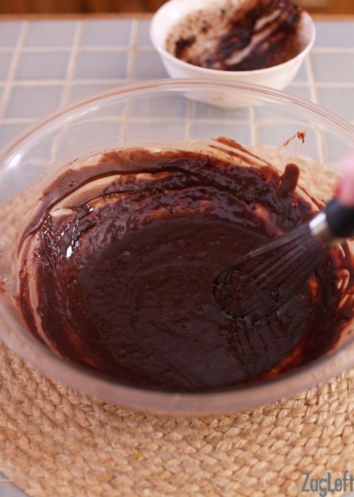 Melted chocolate and chocolate mixture in glass bowl with a whisk