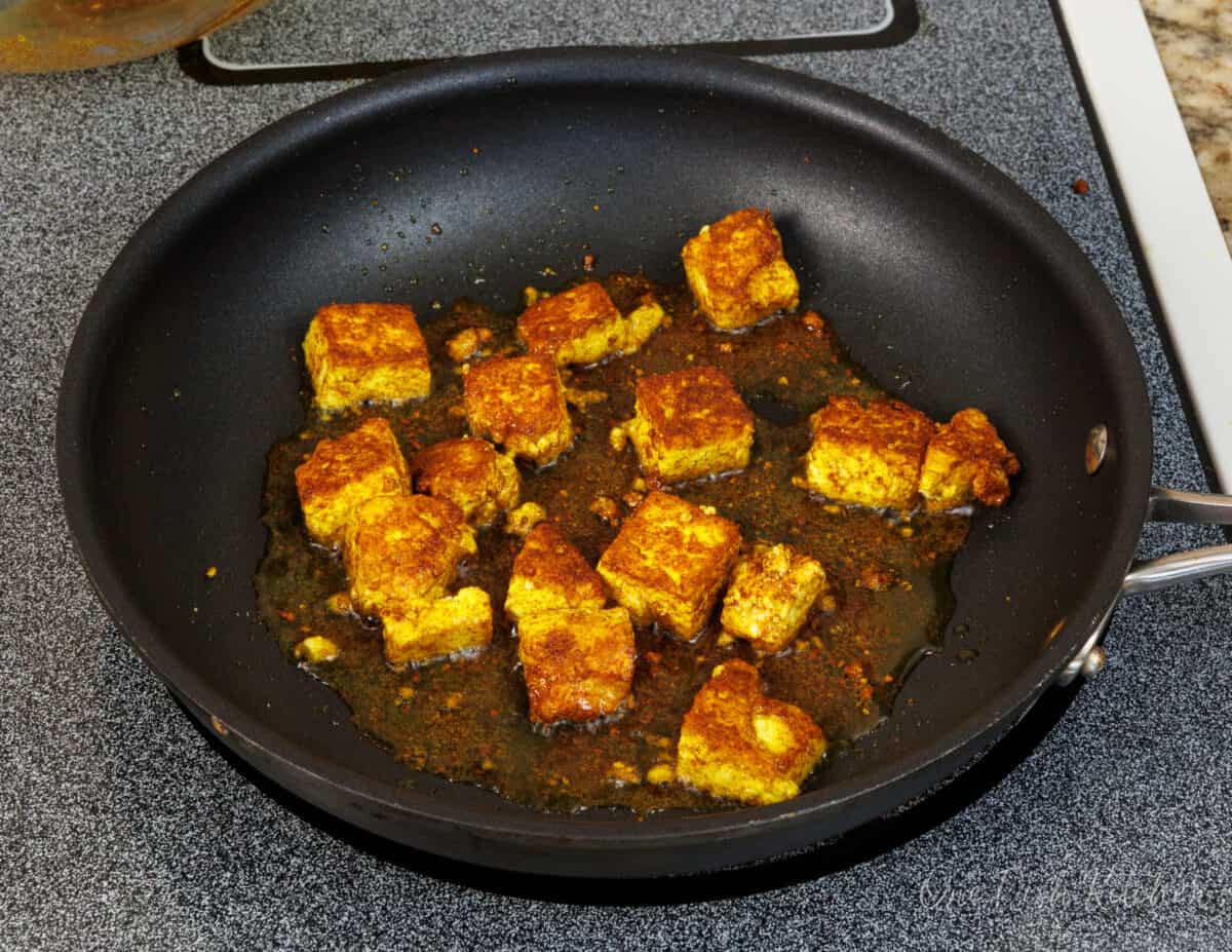 cubes of pan fried paneer in a skillet.