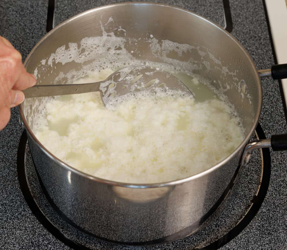 hot milk mixed with lemon juice causing curdling in a pot.