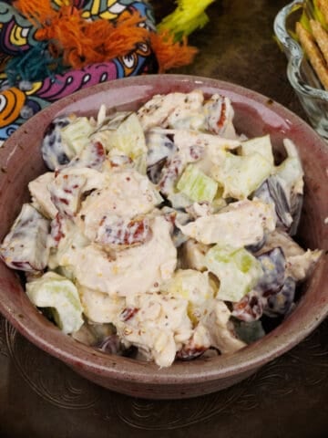 a bowl filled with chicken salad with grapes next to a bowl of crackers