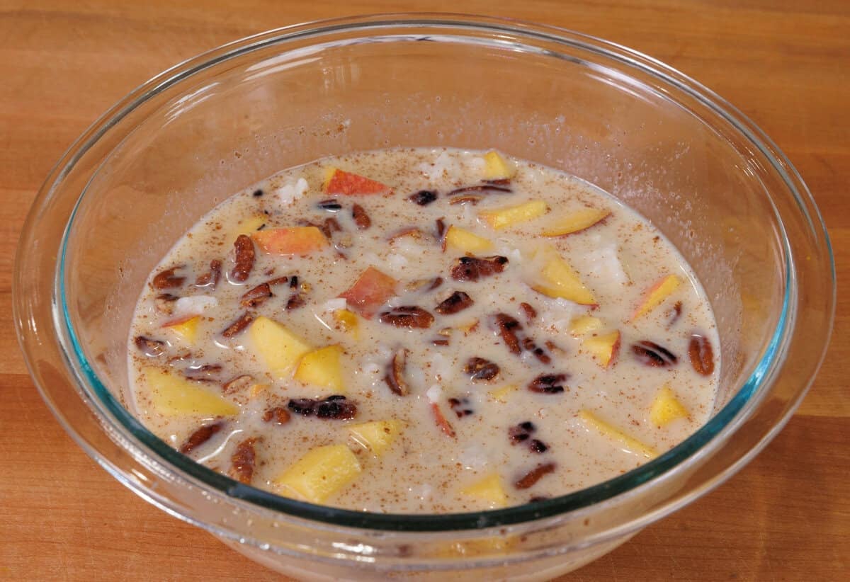 a bowl filled with cooked rice, milk, spices, an egg, and peaches for rice pudding.