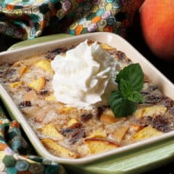 a small peach rice pudding in a green baking dish topped with whipped cream and fresh mint
