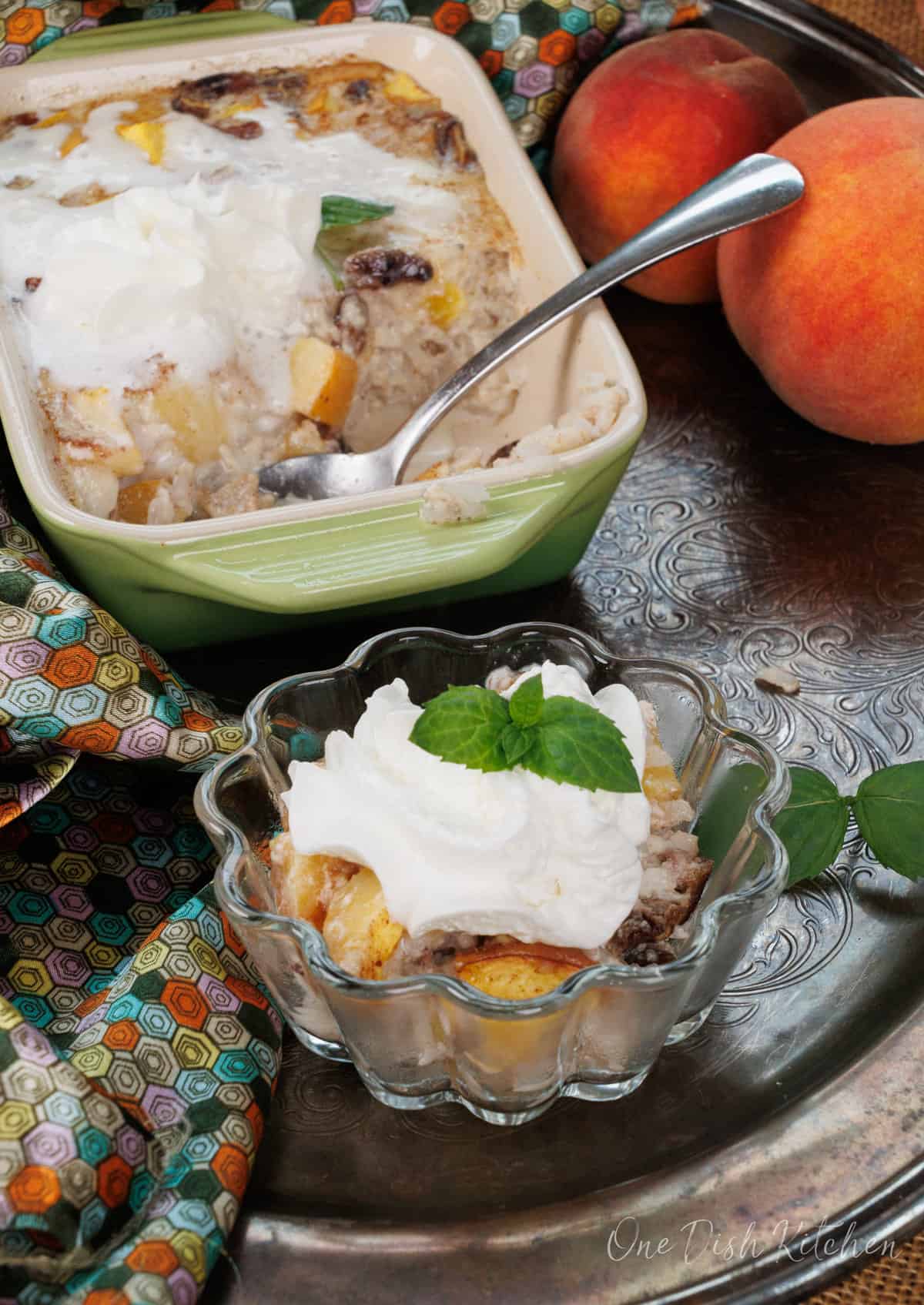 a bowl of peaches and cream rice pudding next to a larger dish on a silver tray