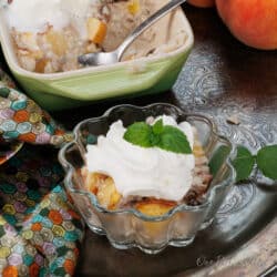 a bowl of peaches and cream rice pudding next to a larger dish on a silver tray