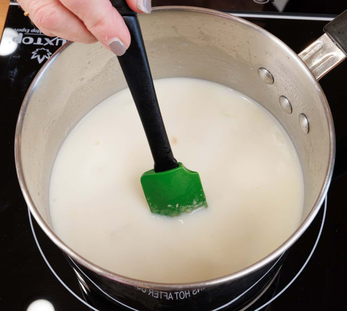 cream and milk being stirred into a soup