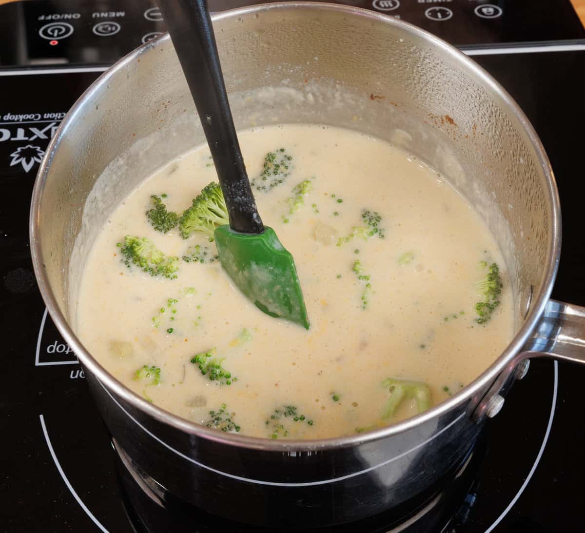broccoli cheddar soup simmering in a pot on the stove