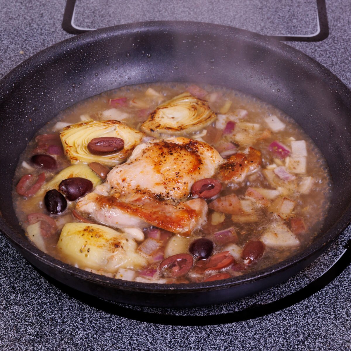mediterranean chicken cooking in a skillet.