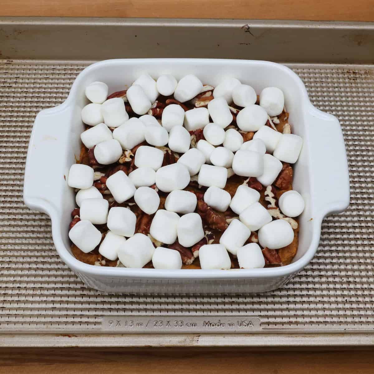 an unbaked sweet potato casserole with marshmallows in a white baking dish.