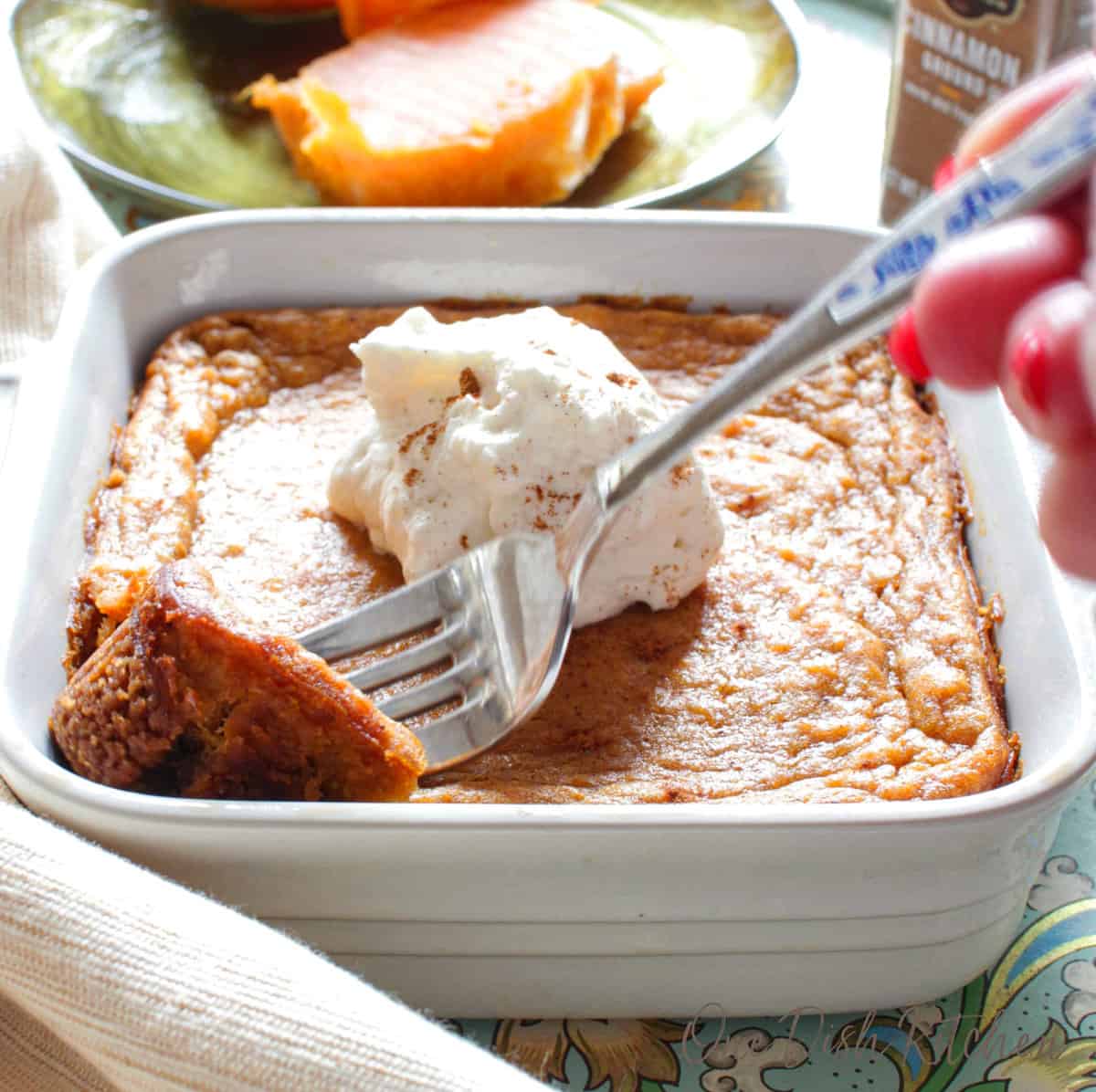 a fork on the side of a serving of sweet potato pie with whipped cream.