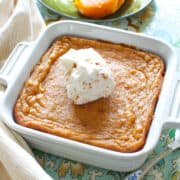 a small sweet potato pie in a square baking dish next to a plate of sliced sweet potatoes