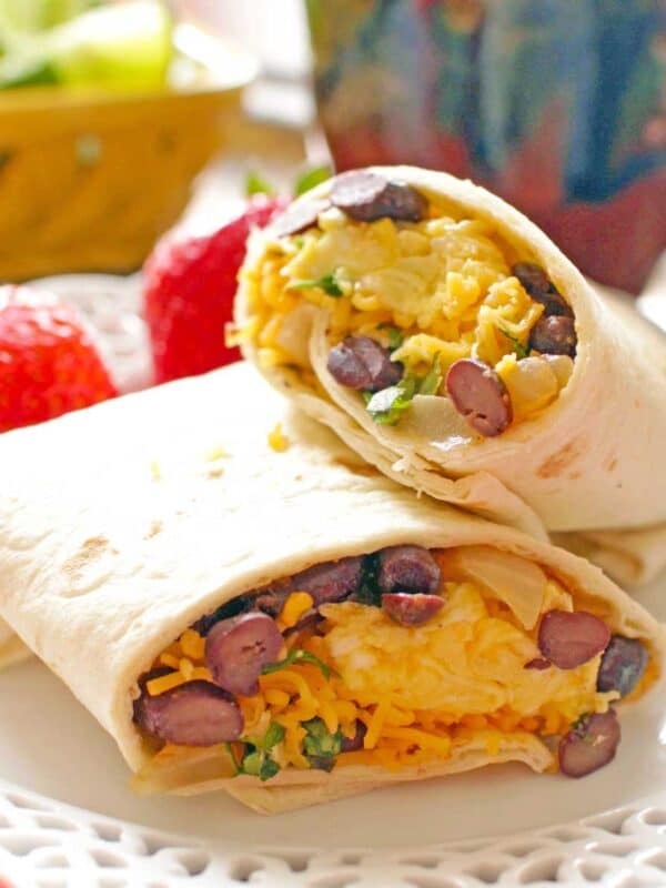egg, sausage and cheese wrapped up in tortillas on a white dish.
