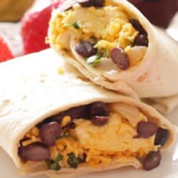 two breakfast burritos filled with beans and cheese on a white plate.