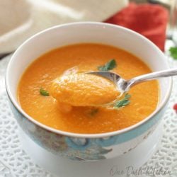 a blue and white bowl filled with carrot soup next to an orange napkin