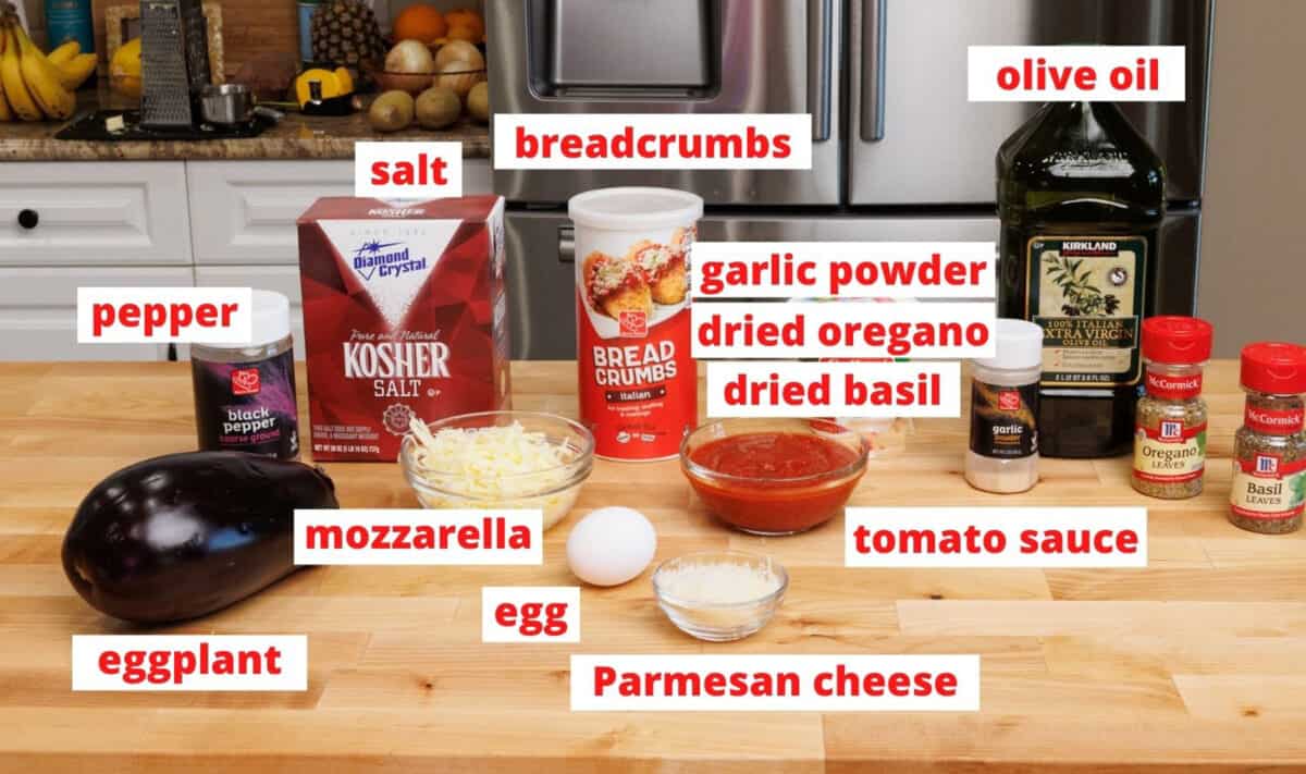 ingredients in eggplant parmesan on a wooden cutting board.