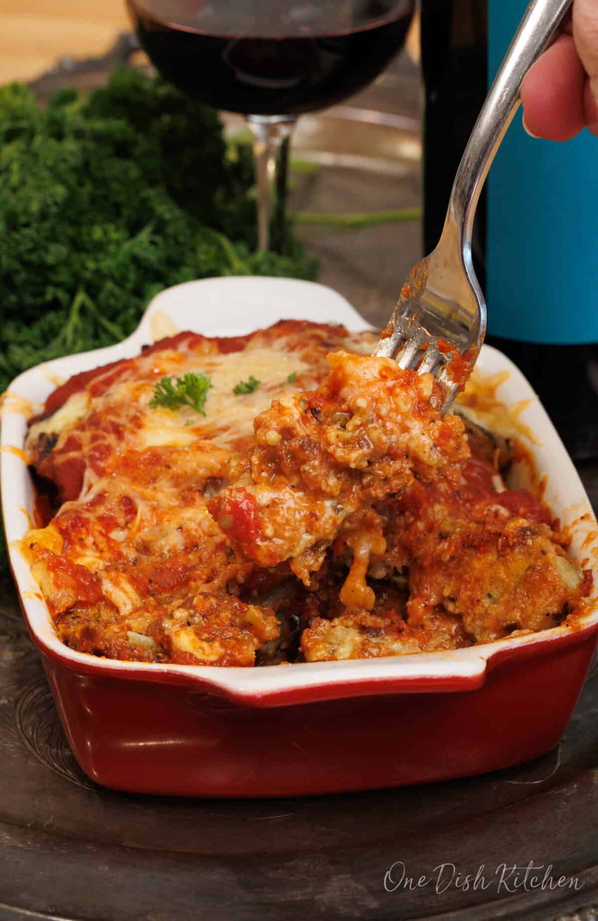 eggplant parmesan in a small baking dish with a fork on the side of the dish.