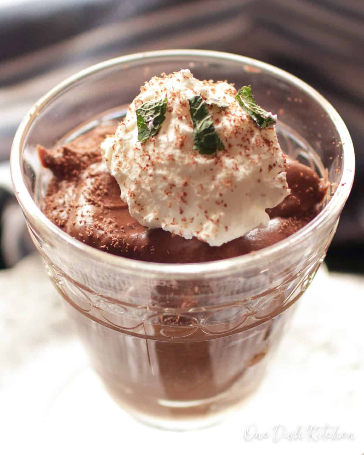 a clear dessert glass filled with chocolate mousse topped with whipped cream.