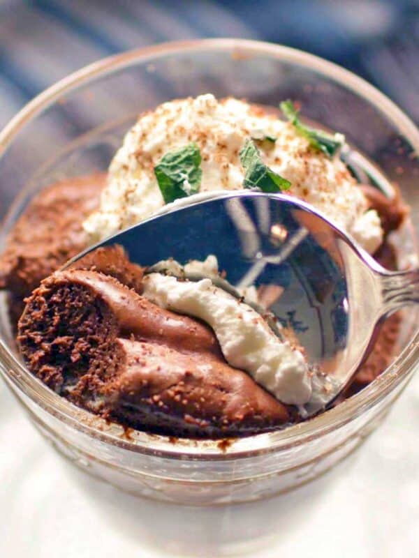 Chocolate Mousse with whipped cream in a small glass bowl with a spoon.
