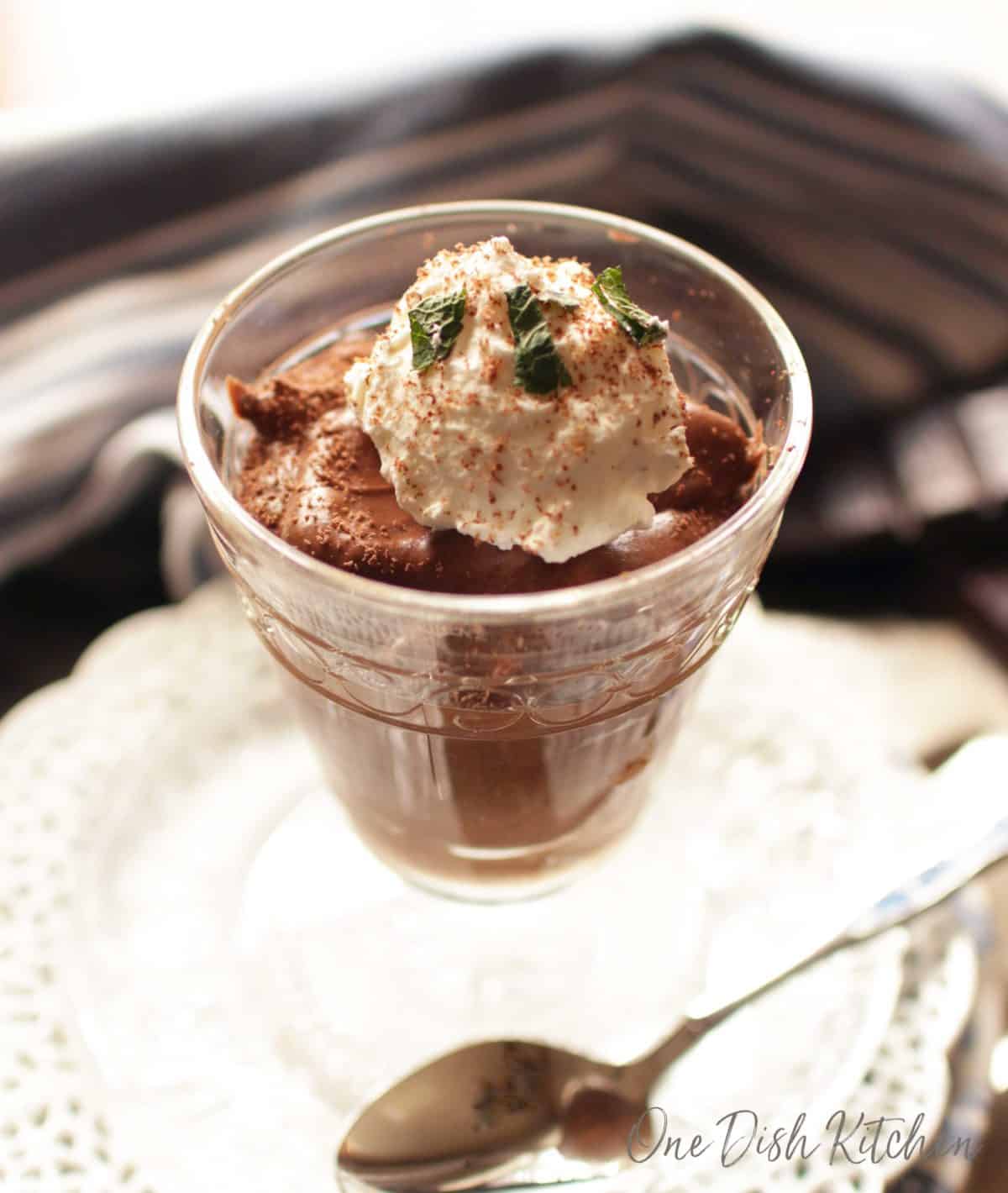 a clear dessert glass filled with chocolate mousse topped with whipped cream.