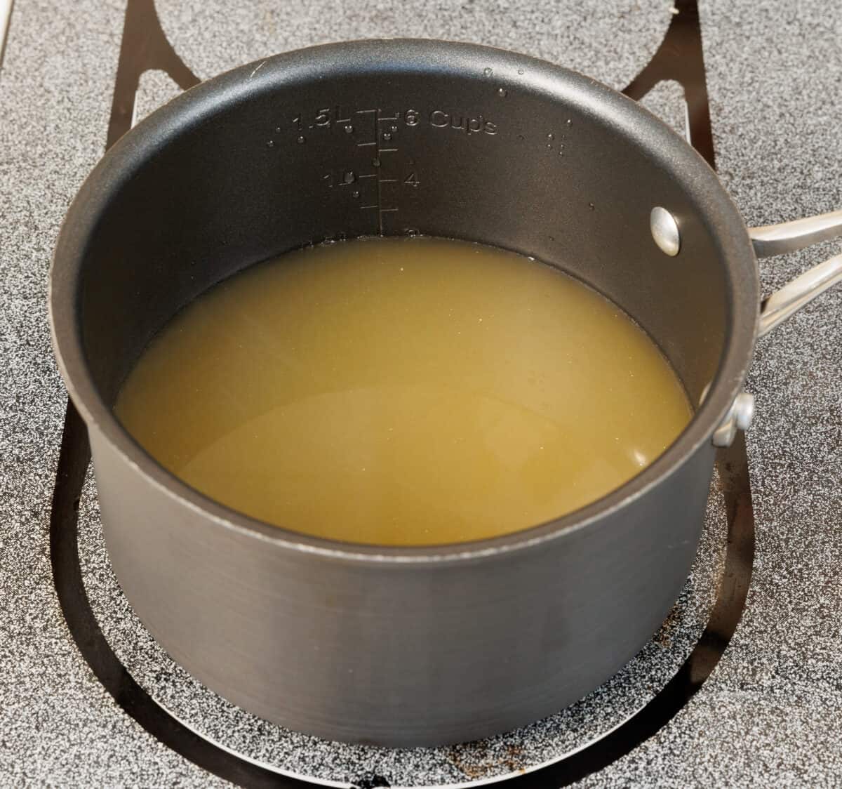 chicken broth in a small pot on the stove.