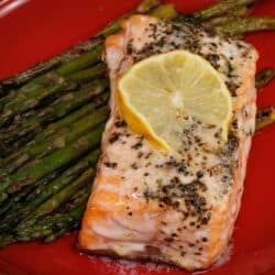 baked salmon on top of roasted asparagus in a red bowl