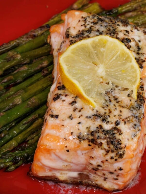 baked salmon on top of roasted asparagus in a red bowl