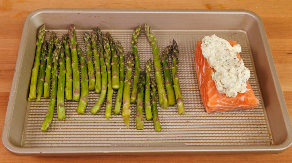 a salmon fillet next to fresh asparagus on a sheet pan