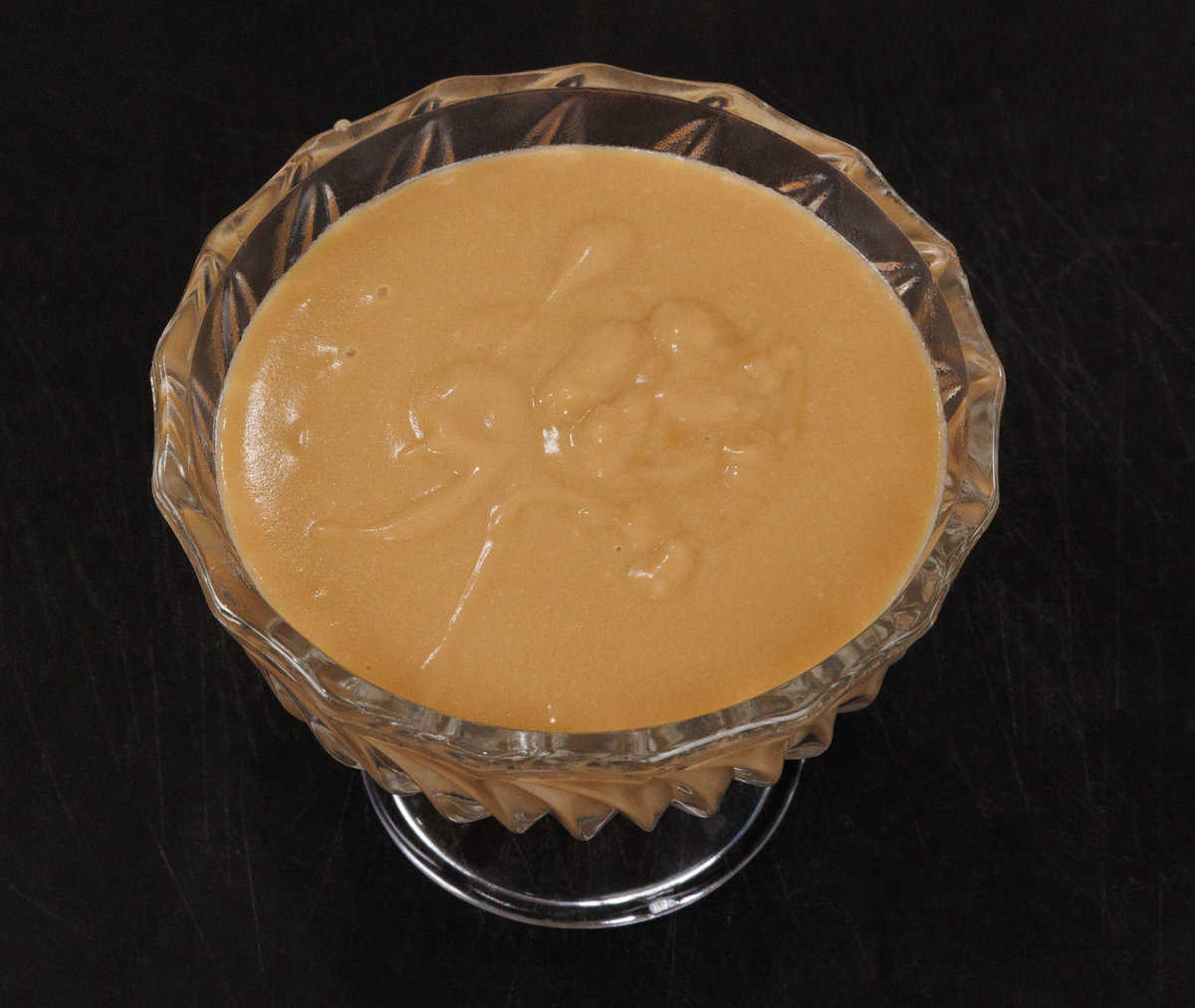 homemade butterscotch in a dessert bowl on a black table