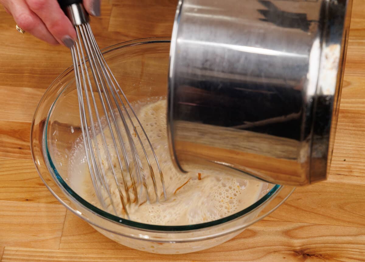 adding hot caramel to a cornstarch slurry in a mixing bowl
