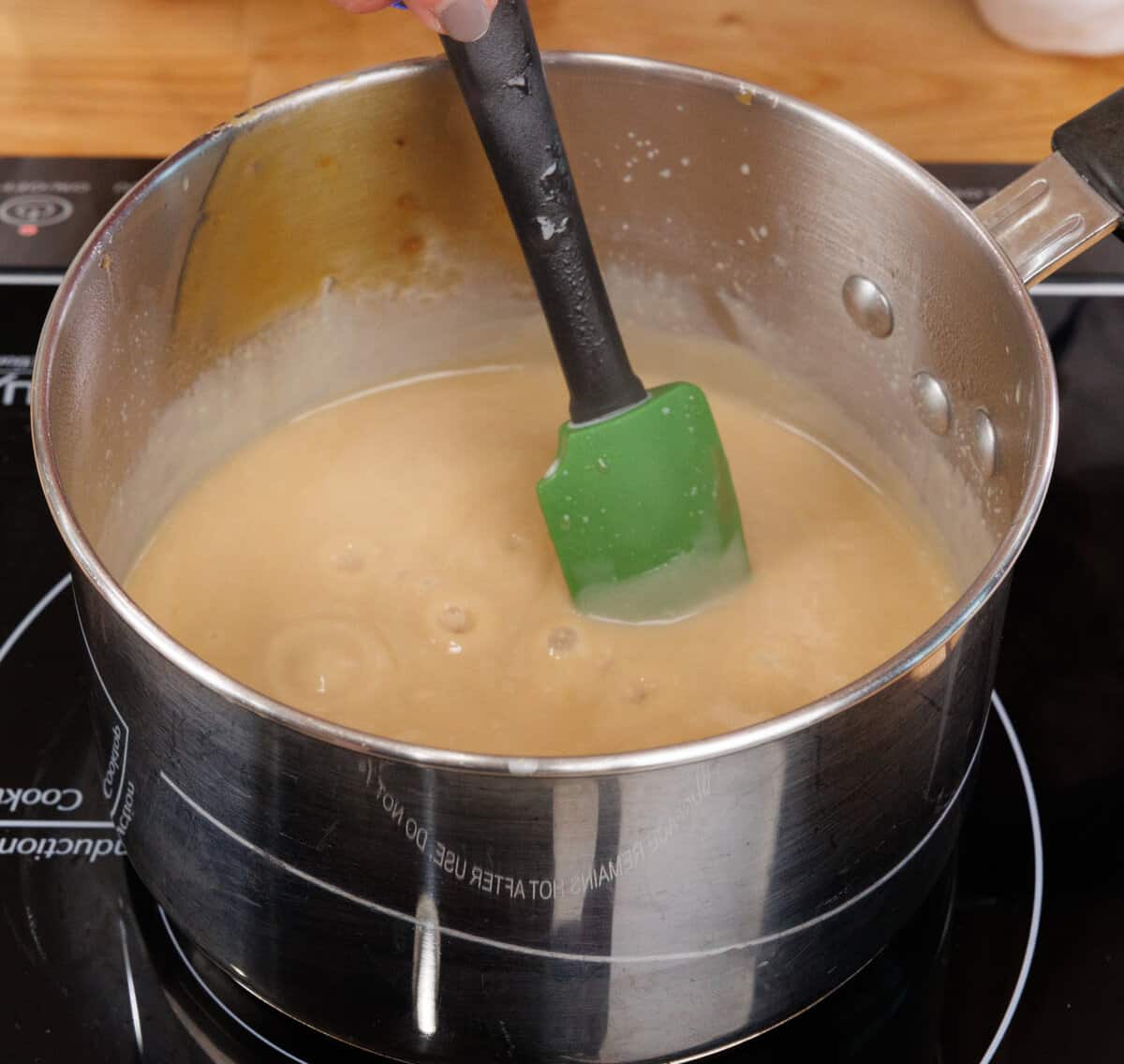 butterscotch pudding in a small saucepan cooking on the stove