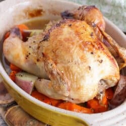a single cornish hen with roasted vegetables on a baking pan.