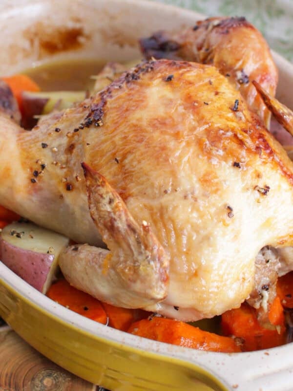 a single cornish hen with roasted vegetables on a baking pan.