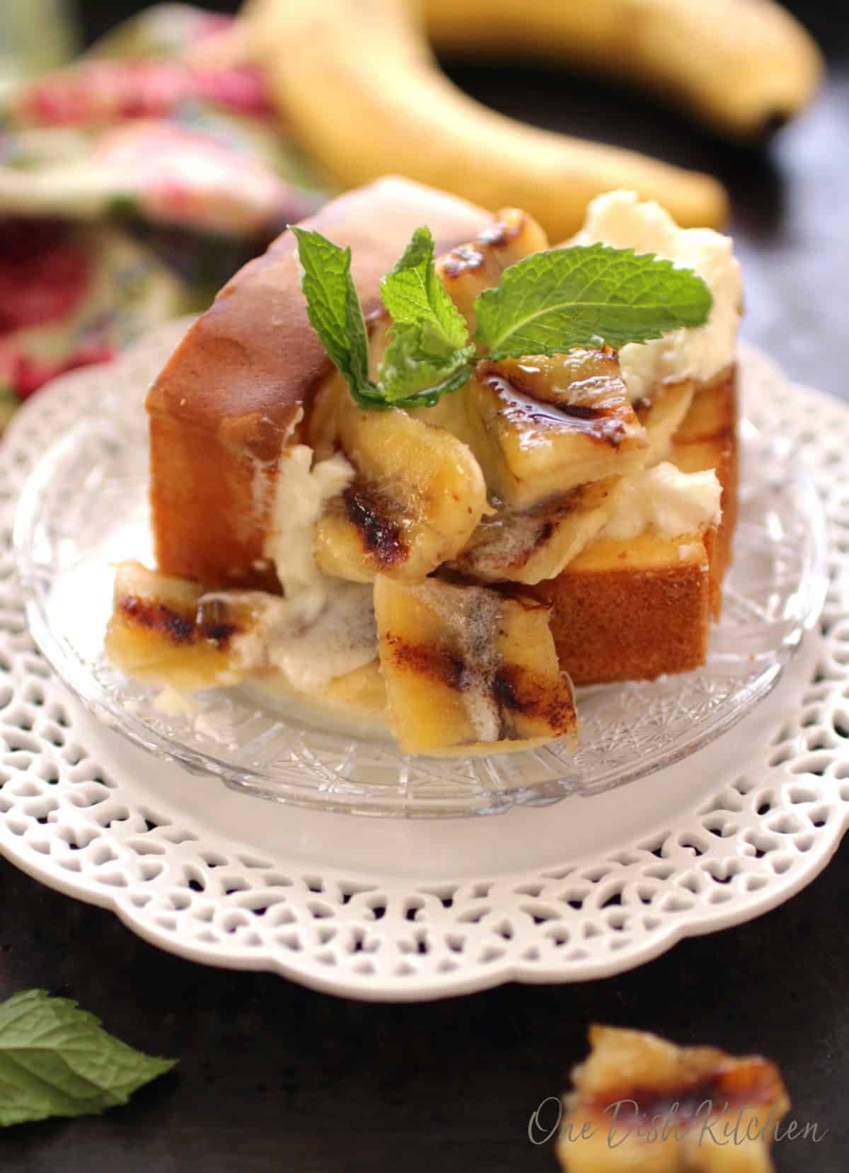 two slices of pound cake topped with sliced bananas and whipped cream on a plate.