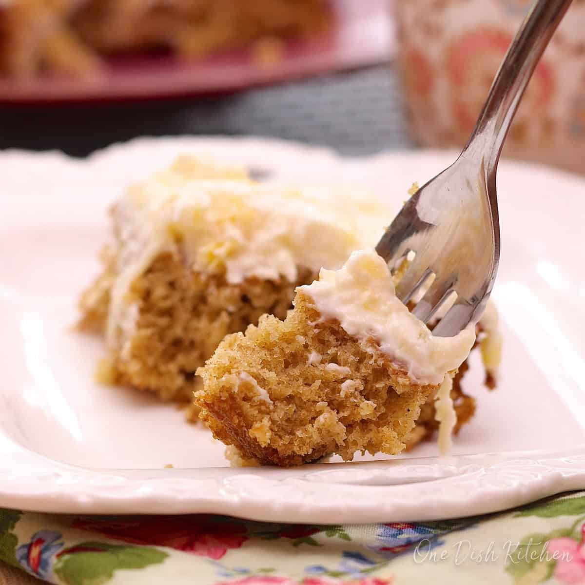 a slice of pineapple oat cake on a white plate next to a fork.