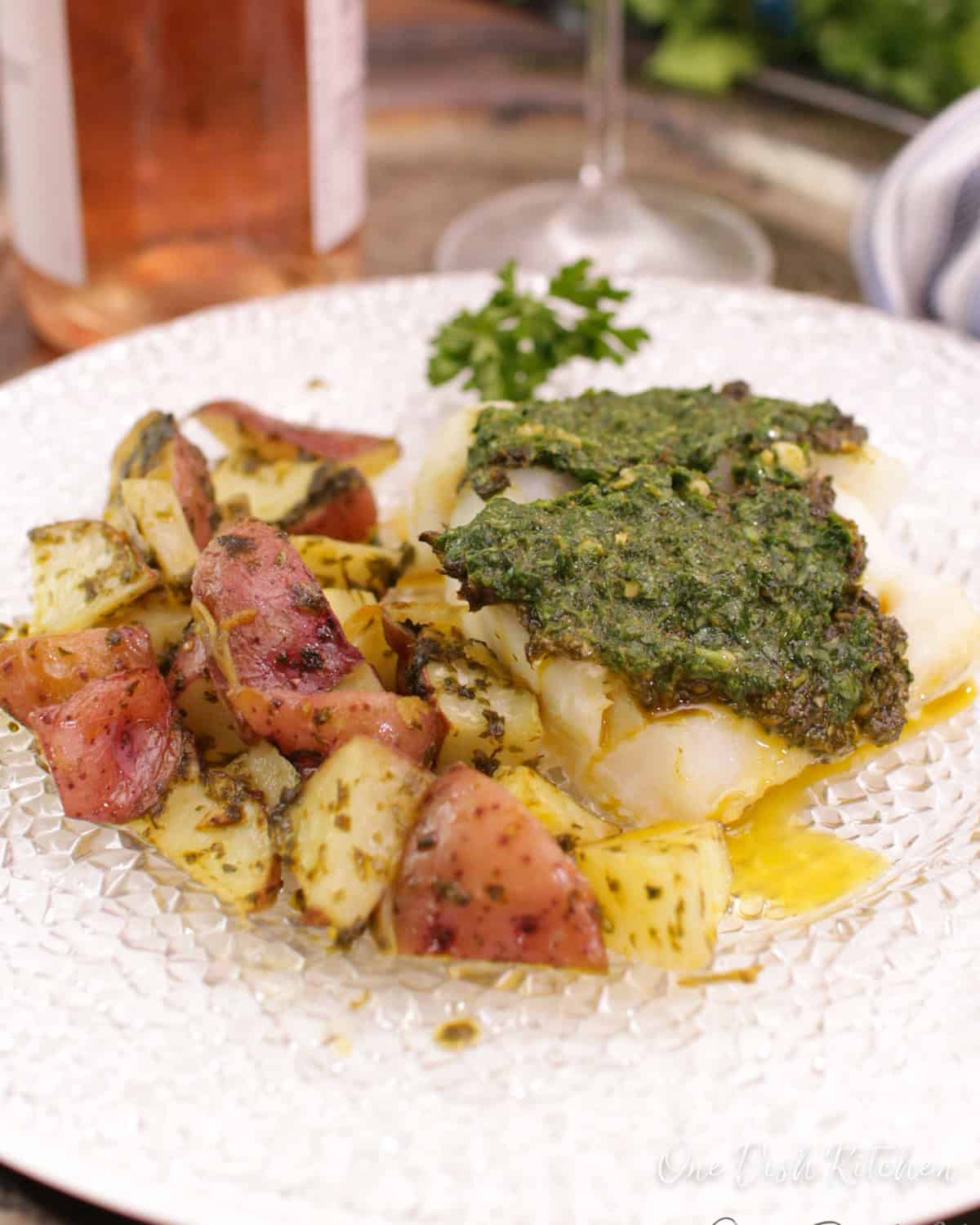 baked cod with chermoula sauce over the top next to roasted potatoes.