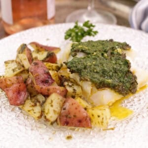 baked cod with chermoula sauce over the top next to roasted potatoes.