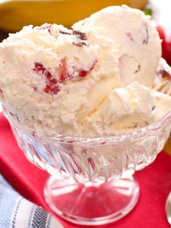 a bowl of strawberry ice cream next to a red napkin.
