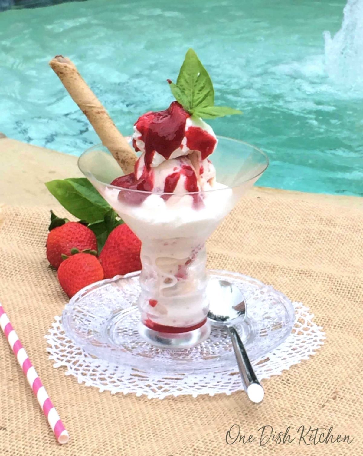 an ice cream sundae in a clear dish next to a swimming pool.