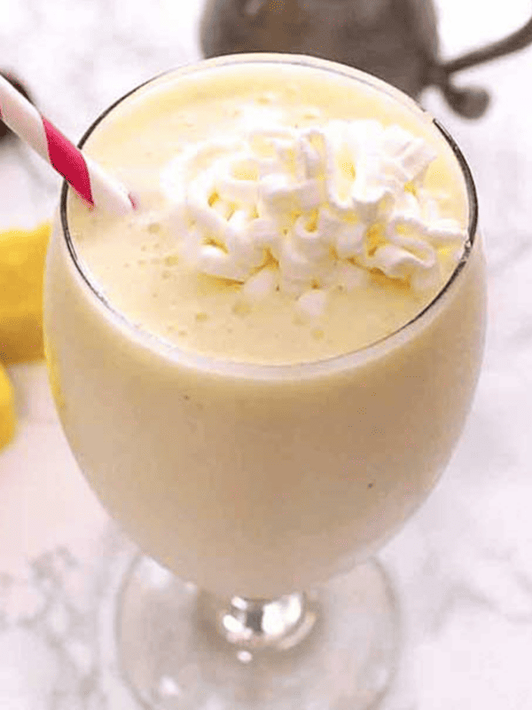 Pina Colada Smoothie in a glass with whipped cream on top.