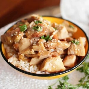 sesame chicken over rice in a yellow bowl