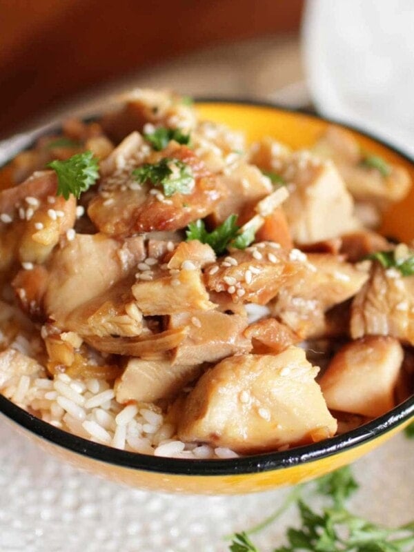 sesame chicken over rice in a yellow bowl